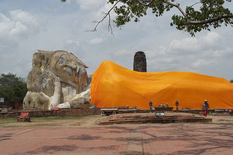 พระนอนองค์ใหญ่ห่มผ้าสีเหลืองส้มกลางลานโบราณสถาน